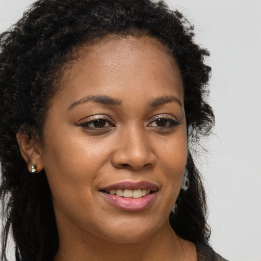 Joyful black young-adult female with long  brown hair and brown eyes