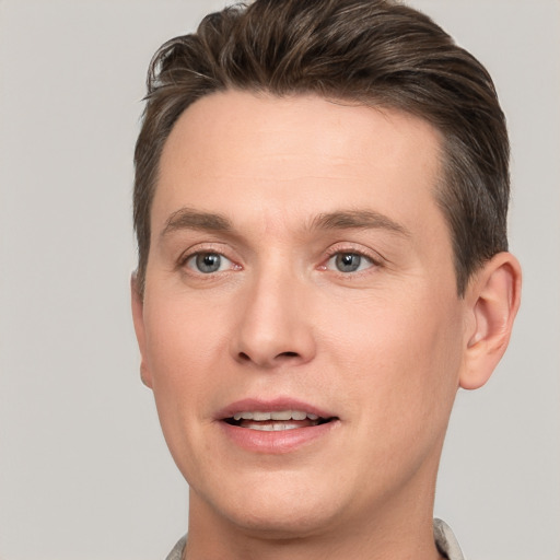 Joyful white young-adult male with short  brown hair and grey eyes