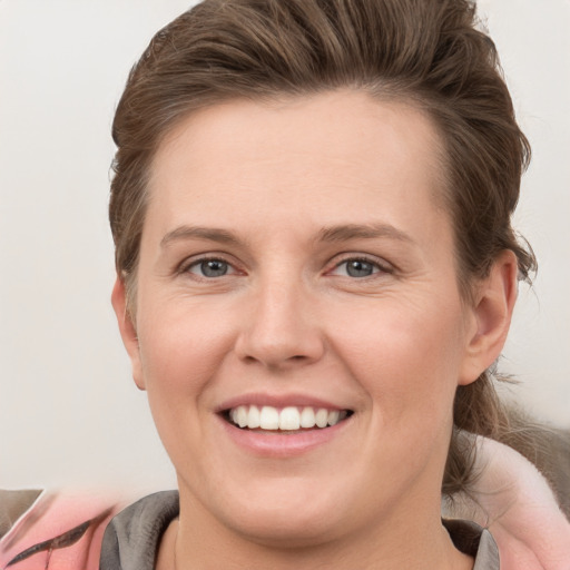 Joyful white young-adult female with medium  brown hair and grey eyes