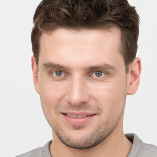 Joyful white young-adult male with short  brown hair and grey eyes