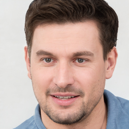 Joyful white young-adult male with short  brown hair and grey eyes