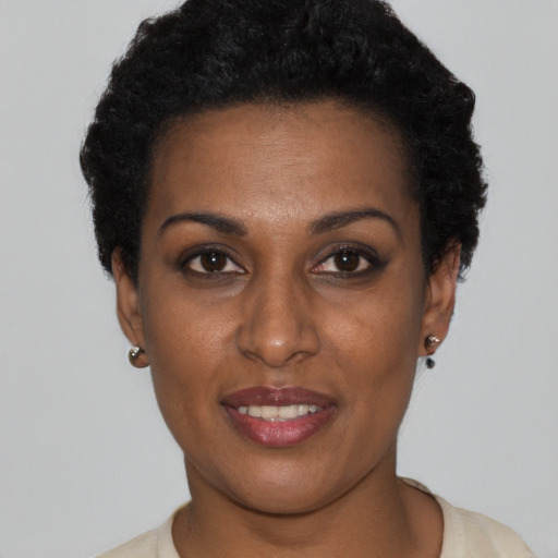 Joyful black young-adult female with short  black hair and brown eyes
