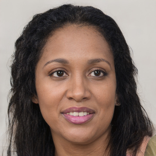 Joyful black young-adult female with long  brown hair and brown eyes