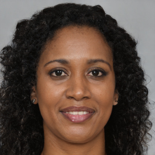 Joyful black young-adult female with long  brown hair and brown eyes
