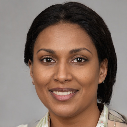 Joyful latino adult female with medium  black hair and brown eyes