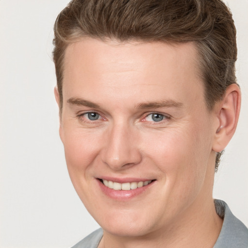 Joyful white young-adult male with short  brown hair and grey eyes