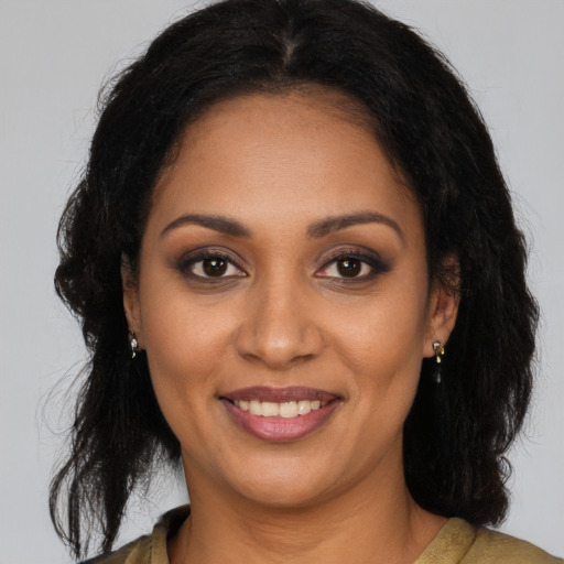 Joyful black young-adult female with long  brown hair and brown eyes