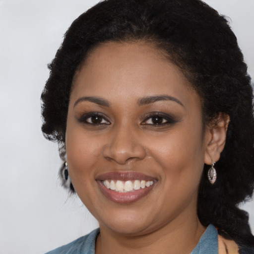 Joyful black young-adult female with long  brown hair and brown eyes