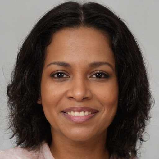 Joyful black young-adult female with long  brown hair and brown eyes