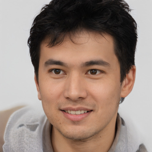 Joyful asian young-adult male with short  brown hair and brown eyes