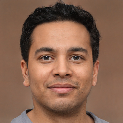 Joyful latino young-adult male with short  brown hair and brown eyes