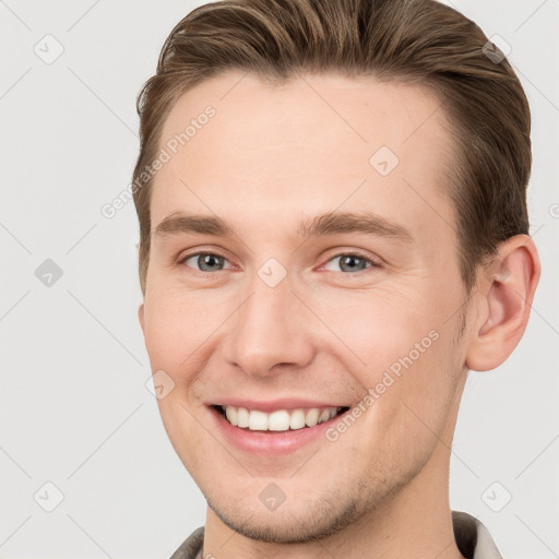 Joyful white young-adult male with short  brown hair and grey eyes