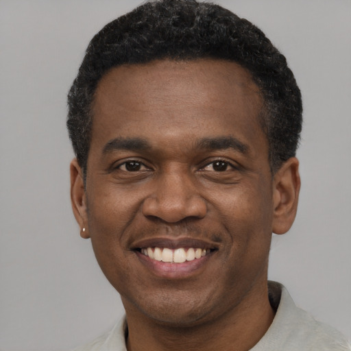 Joyful black young-adult male with short  black hair and brown eyes