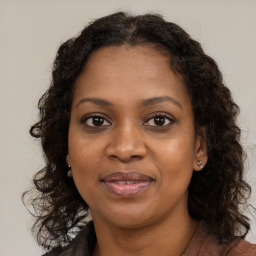 Joyful black young-adult female with long  brown hair and brown eyes