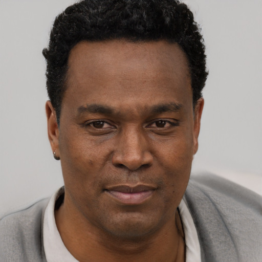 Joyful black young-adult male with short  black hair and brown eyes