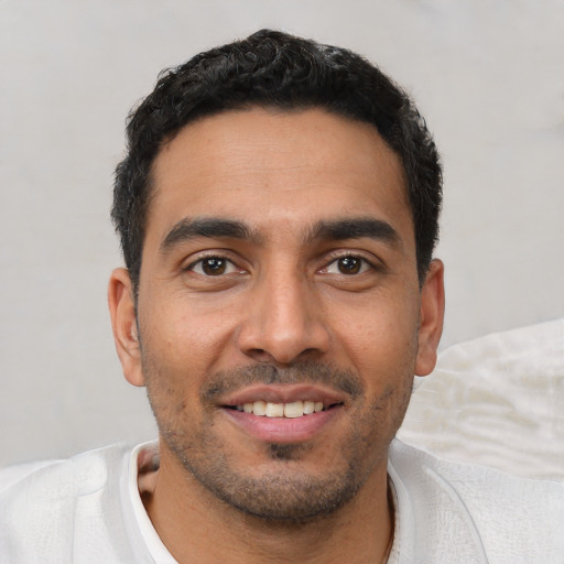 Joyful latino young-adult male with short  black hair and brown eyes