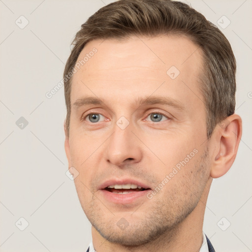 Joyful white young-adult male with short  brown hair and grey eyes