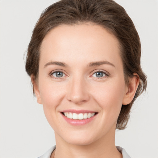 Joyful white young-adult female with medium  brown hair and green eyes