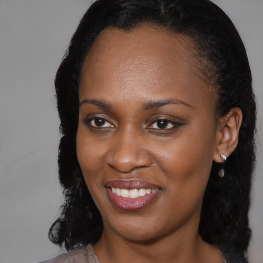 Joyful black young-adult female with long  brown hair and brown eyes