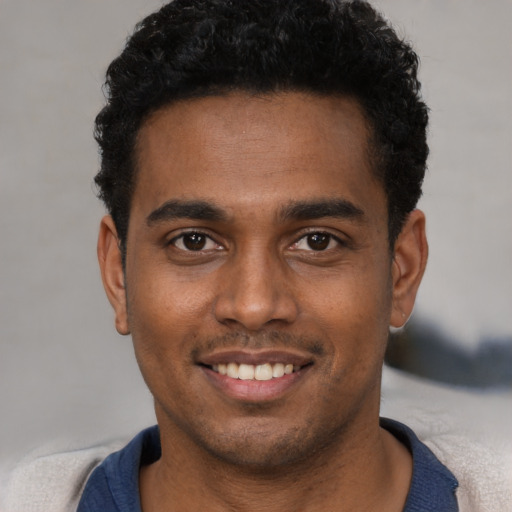 Joyful black young-adult male with short  brown hair and brown eyes