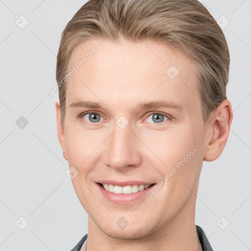 Joyful white young-adult male with short  brown hair and grey eyes