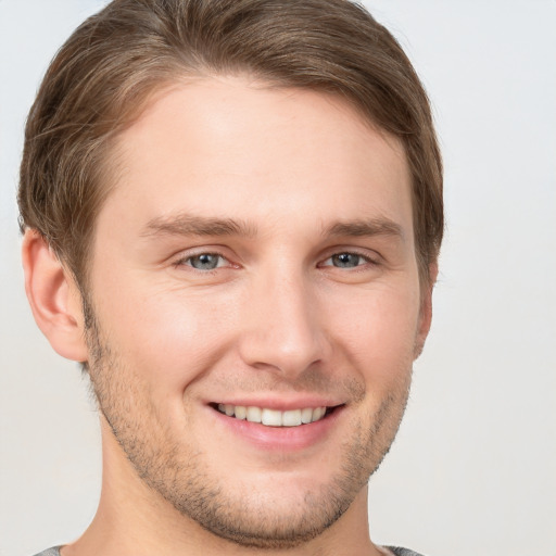 Joyful white young-adult male with short  brown hair and grey eyes