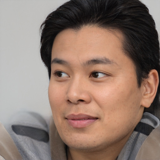 Joyful asian young-adult male with medium  brown hair and brown eyes