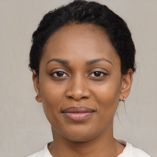 Joyful black young-adult female with short  black hair and brown eyes