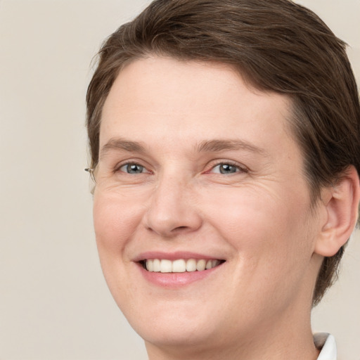 Joyful white young-adult female with short  brown hair and green eyes