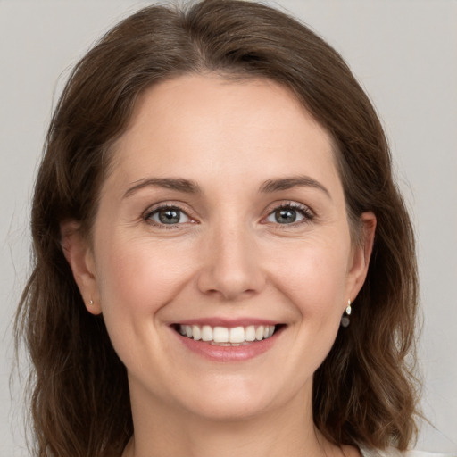 Joyful white young-adult female with medium  brown hair and grey eyes