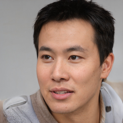 Joyful asian young-adult male with short  brown hair and brown eyes