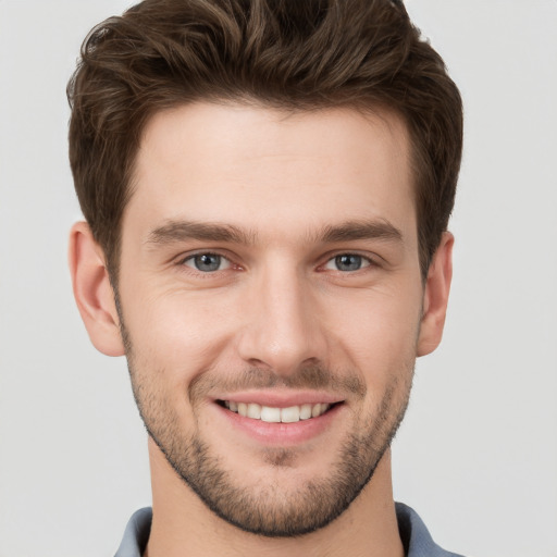 Joyful white young-adult male with short  brown hair and grey eyes