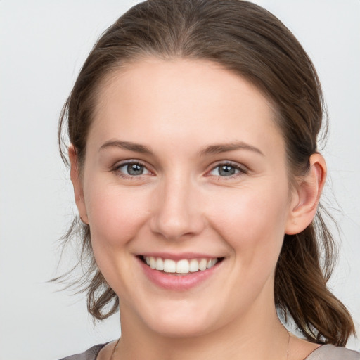 Joyful white young-adult female with medium  brown hair and grey eyes