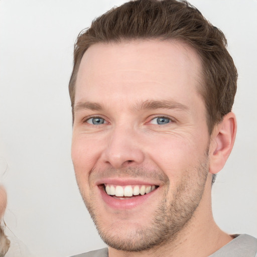 Joyful white young-adult male with short  brown hair and grey eyes