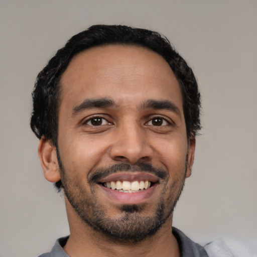 Joyful latino young-adult male with short  black hair and brown eyes