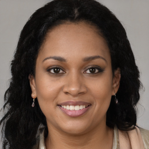 Joyful black young-adult female with long  brown hair and brown eyes