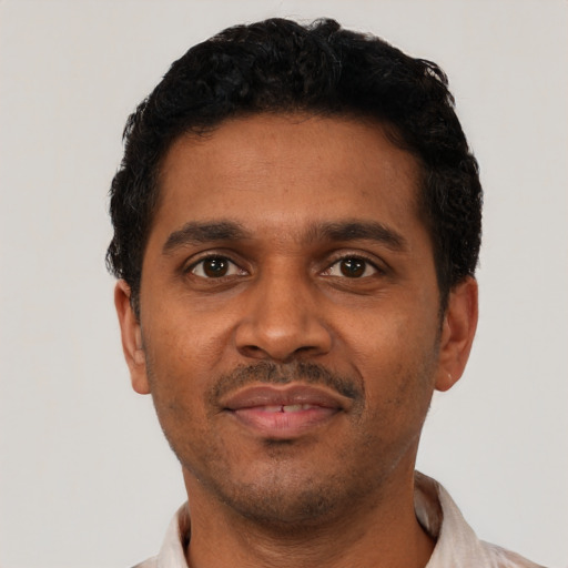 Joyful black young-adult male with short  black hair and brown eyes