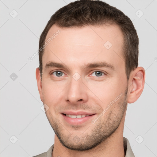 Joyful white young-adult male with short  brown hair and grey eyes