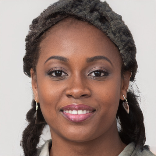 Joyful black young-adult female with long  brown hair and brown eyes