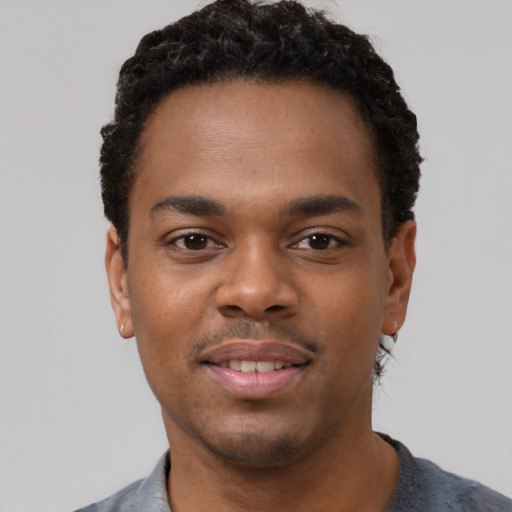 Joyful black young-adult male with short  black hair and brown eyes