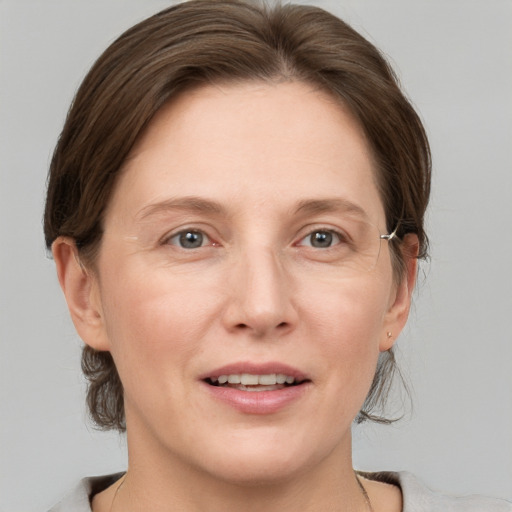 Joyful white adult female with medium  brown hair and grey eyes