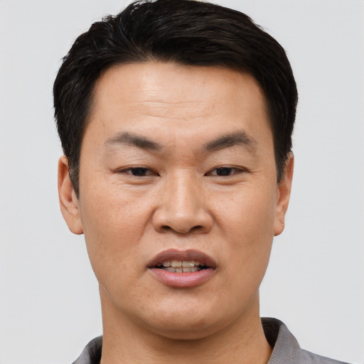 Joyful asian adult male with short  black hair and brown eyes