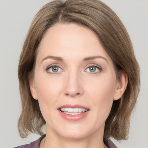 Joyful white young-adult female with medium  brown hair and grey eyes