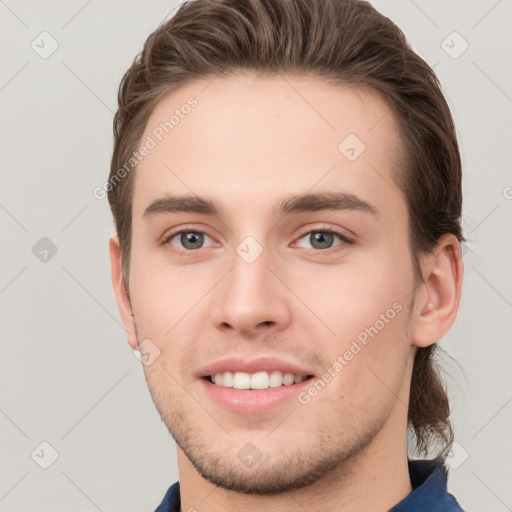 Joyful white young-adult male with short  brown hair and grey eyes