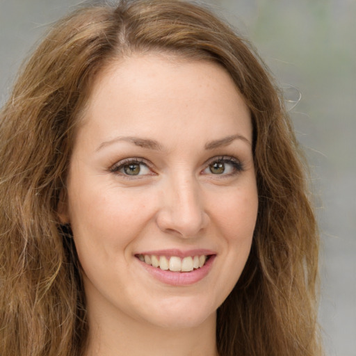 Joyful white young-adult female with long  brown hair and green eyes