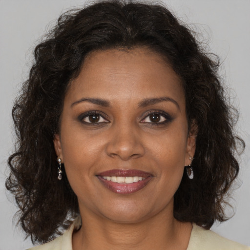 Joyful black adult female with long  brown hair and brown eyes