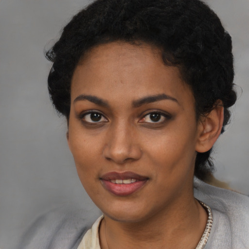 Joyful black young-adult female with short  black hair and brown eyes