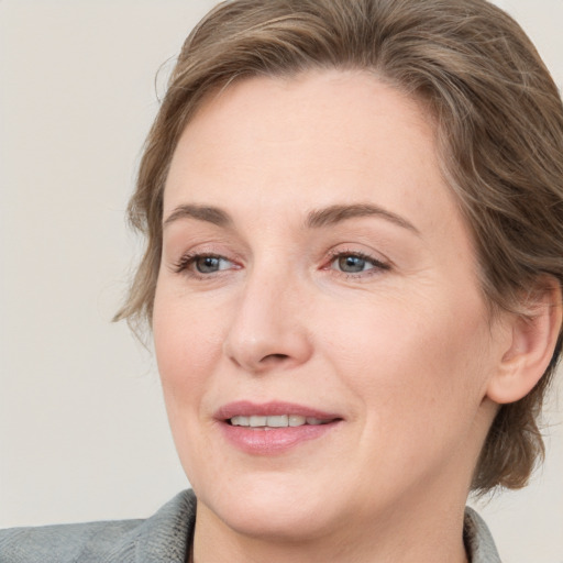 Joyful white adult female with medium  brown hair and grey eyes