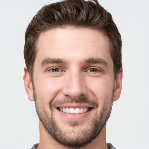 Joyful white young-adult male with short  brown hair and grey eyes