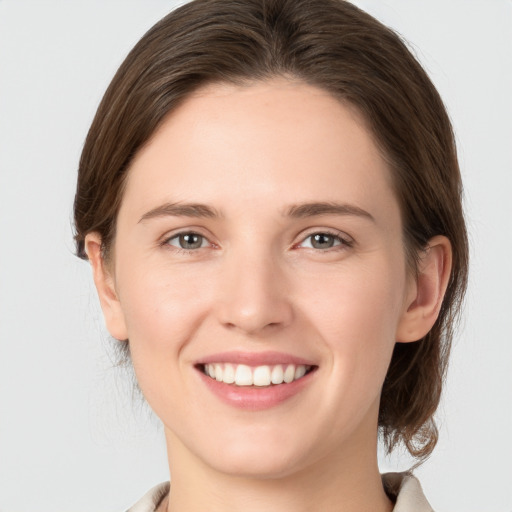 Joyful white young-adult female with medium  brown hair and grey eyes